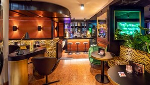 A modern bar area with a curved counter, bar stools, and a seating area with a sofa and round tables. - Central Plaza Hotel (Zürich)
