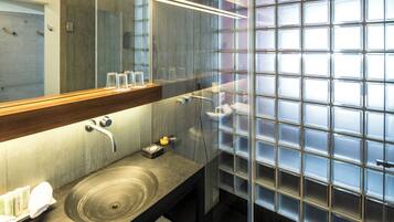A modern bathroom with a large mirror, a sink with a round basin, and a glass shower enclosure.