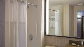 Un baño con ducha, inodoro, lavabo y un espejo grande.