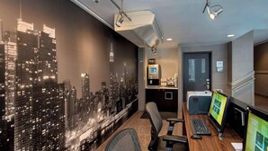 A modern office space with a cityscape mural, a desk with two monitors, a keyboard, and a chair.