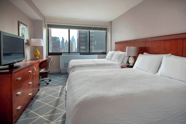 A hotel room with two beds, a TV, a desk, and a window with a city view. - Courtyard by Marriott New York City Manhattan Fifth Avenue (New York)