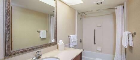 A bathroom with a sink, mirror, toilet, and bathtub.