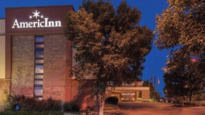 An American Inn hotel with a brick facade, a large tree in front, and a parking lot. - AmericInn by Wyndham Omaha (Omaha)