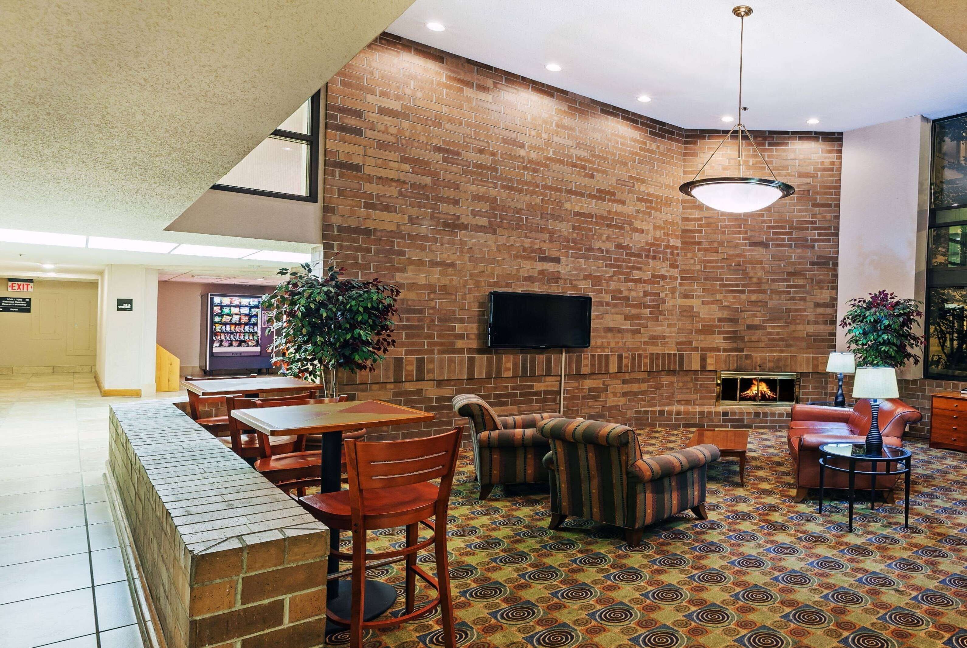 A spacious lobby with a brick wall, a flat-screen TV, a fireplace, and comfortable seating.