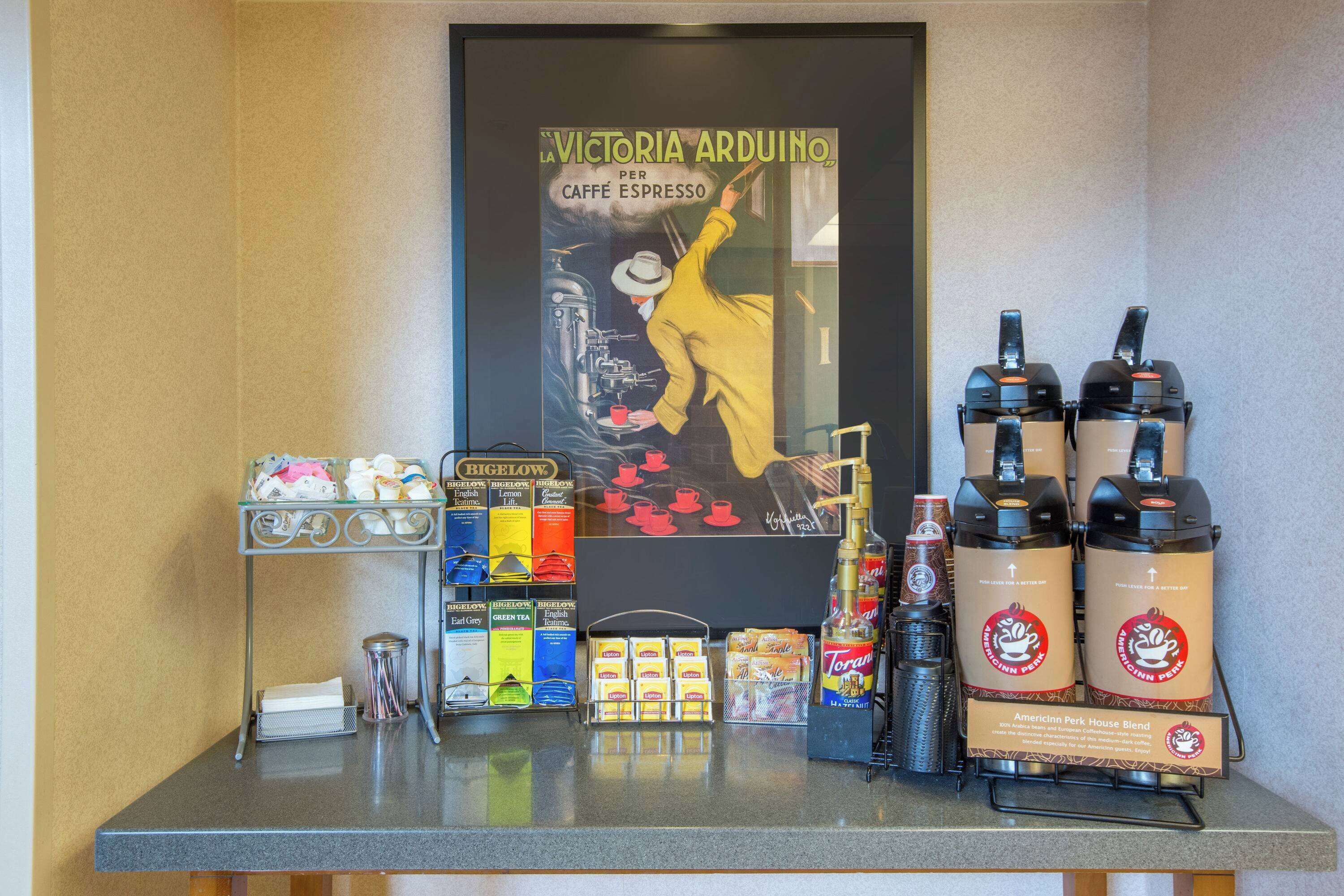 Un coin café proposant différents types de café et agrémenté d’une affiche ancienne.