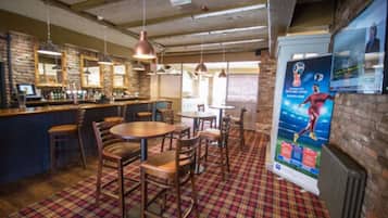 A bar area with wooden furniture, pendant lighting, and a plaid carpet.