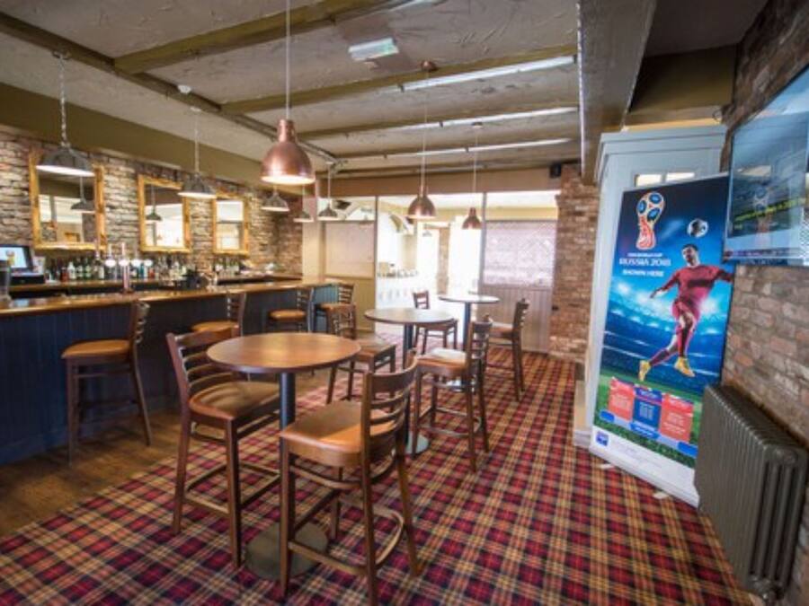 A bar area with wooden furniture, pendant lighting, and a plaid carpet.