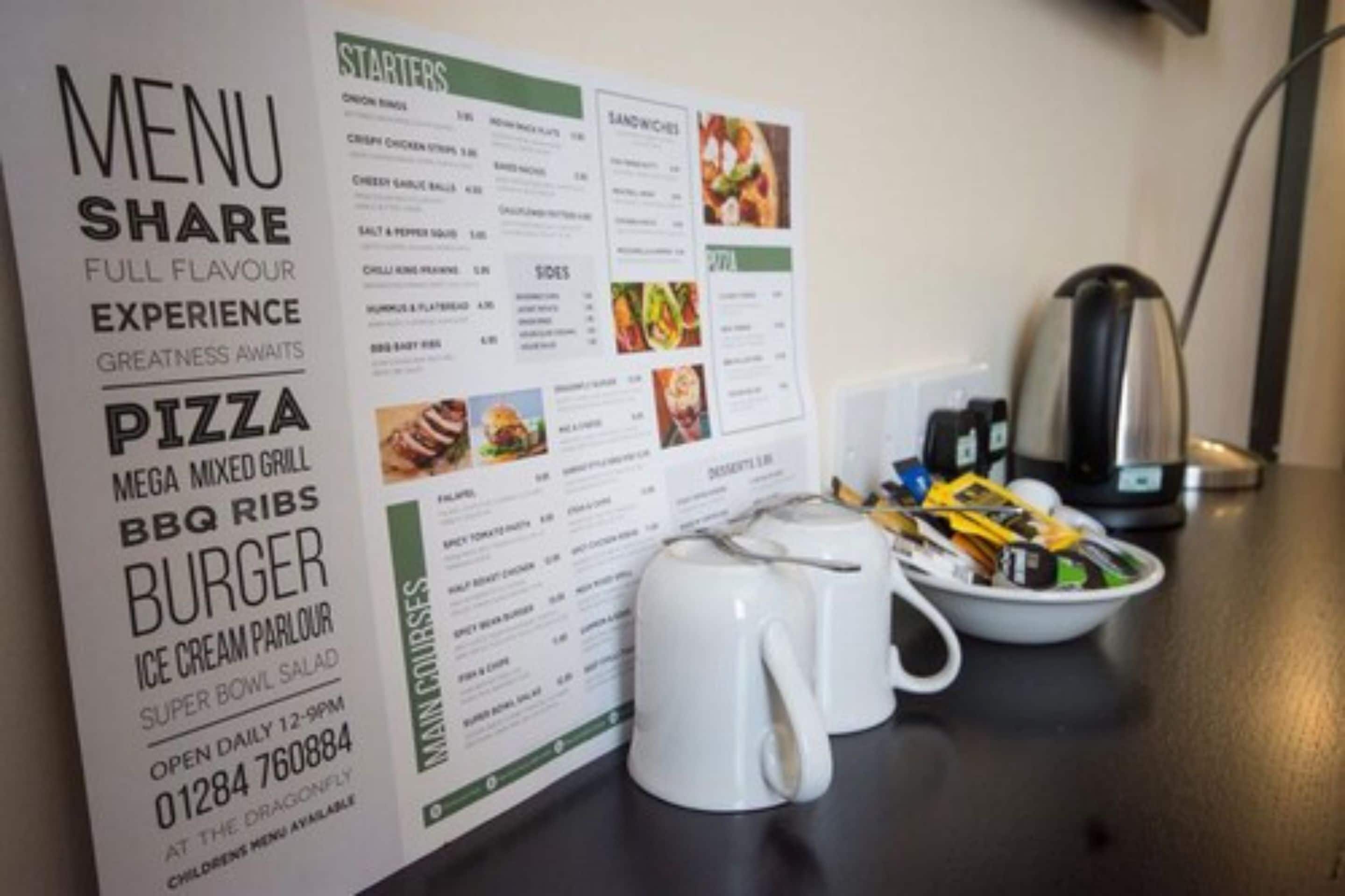 A menu board with various food options and a coffee maker on a table.