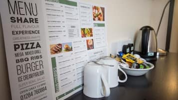 A menu board with various food options and a coffee maker on a table.