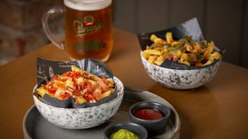 A table with two bowls of food, a beer mug, and small containers of sauces.