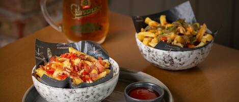 Une table avec deux bols de nourriture, une chope de bière et de petits récipients contenant des sauces.