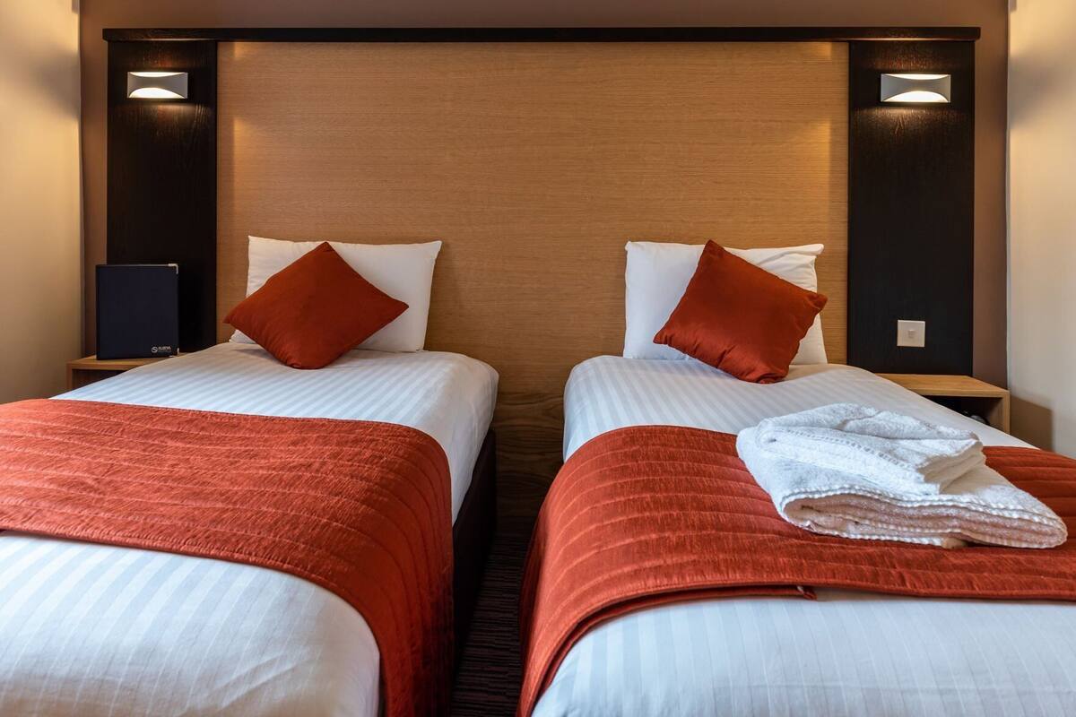 Two twin beds with red bedding, white pillows, and a wooden headboard.