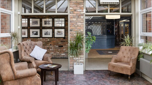 A cozy outdoor seating area with two plush armchairs, a small table, and potted plants. - Dragonfly Hotel Bury St Edmunds (Bury St Edmunds)