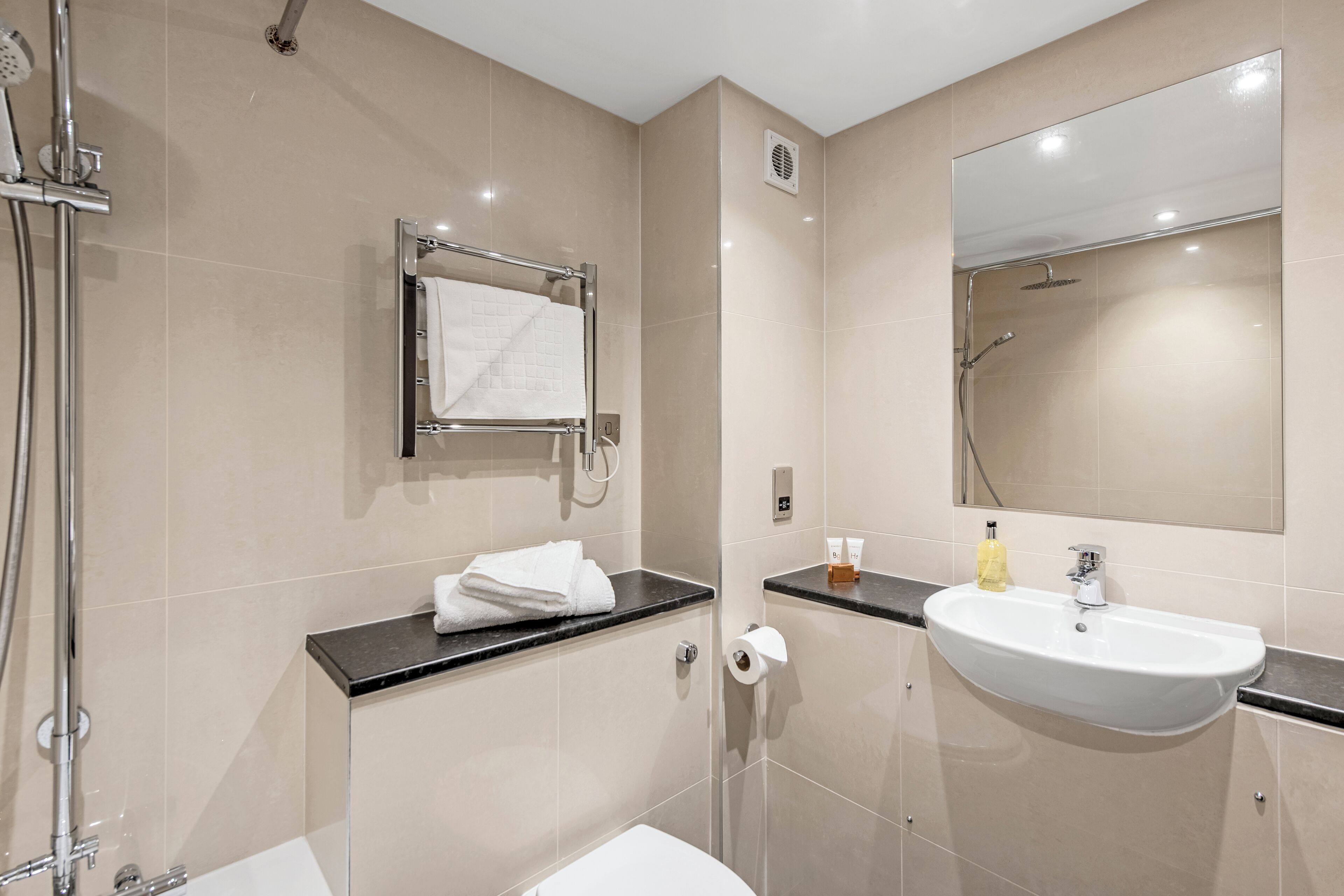 A modern bathroom with a shower, toilet, and sink.
