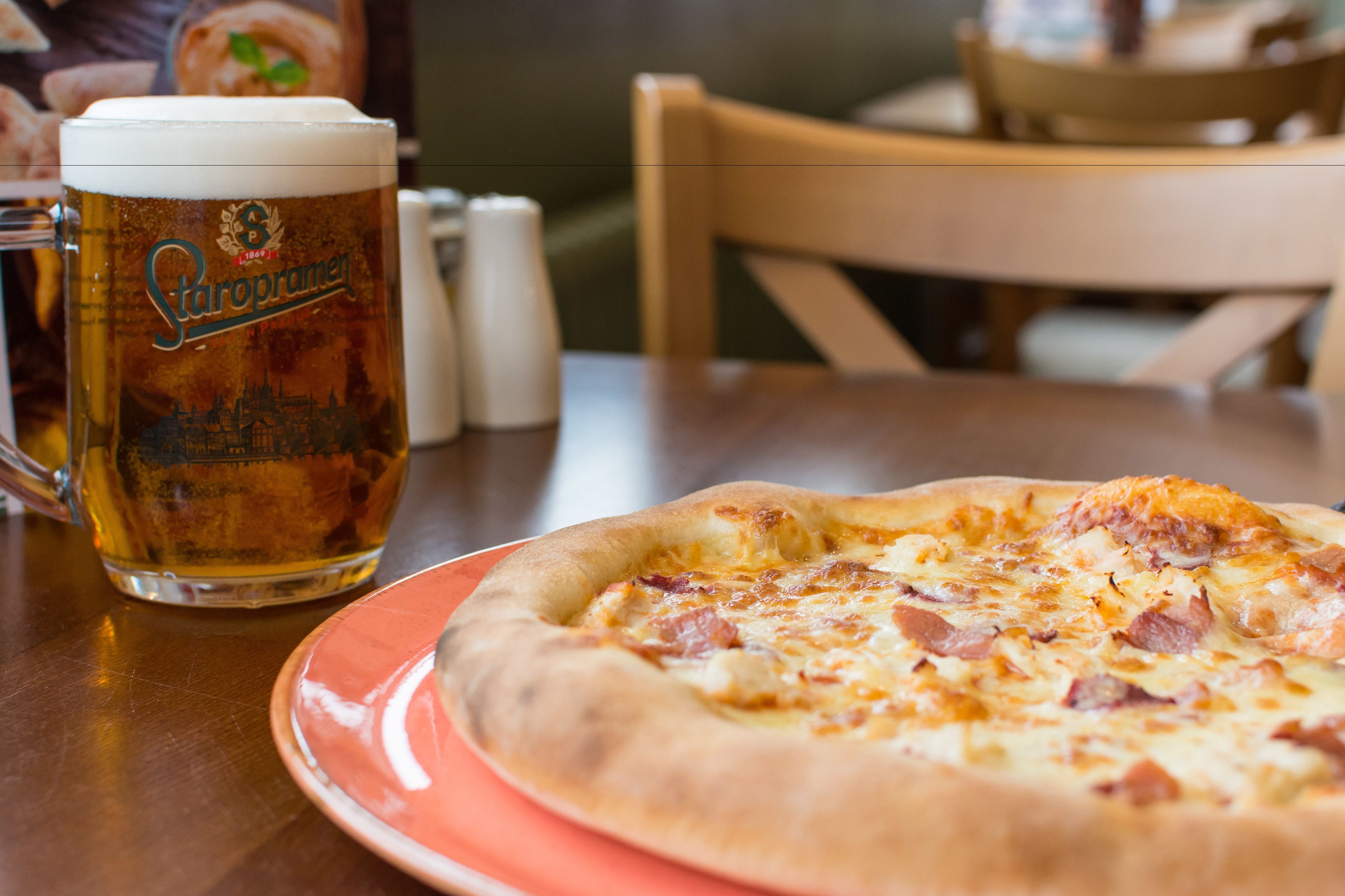 A pizza on a plate with a beer mug beside it.