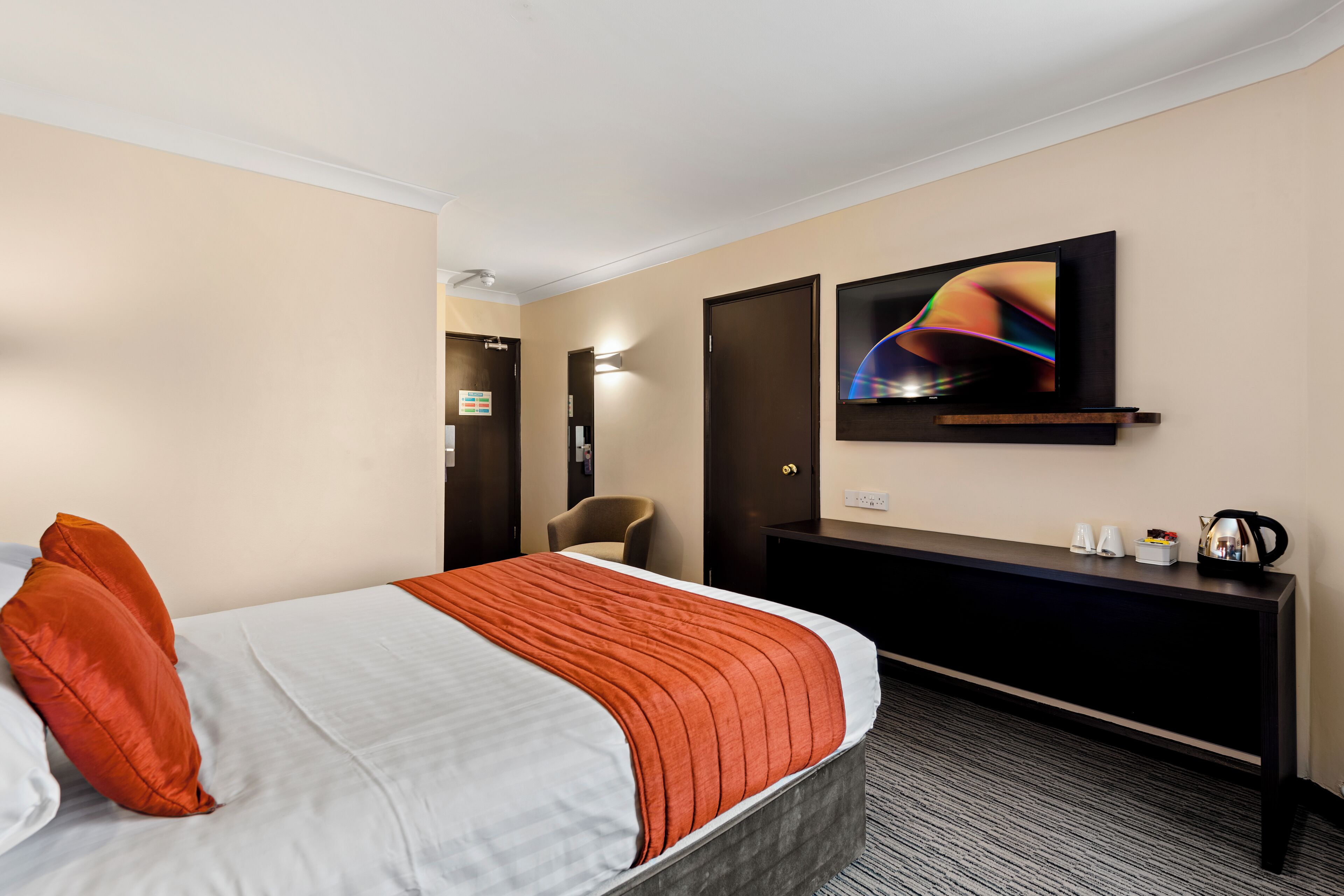 A hotel room with a bed, a desk, a television, and a chair.