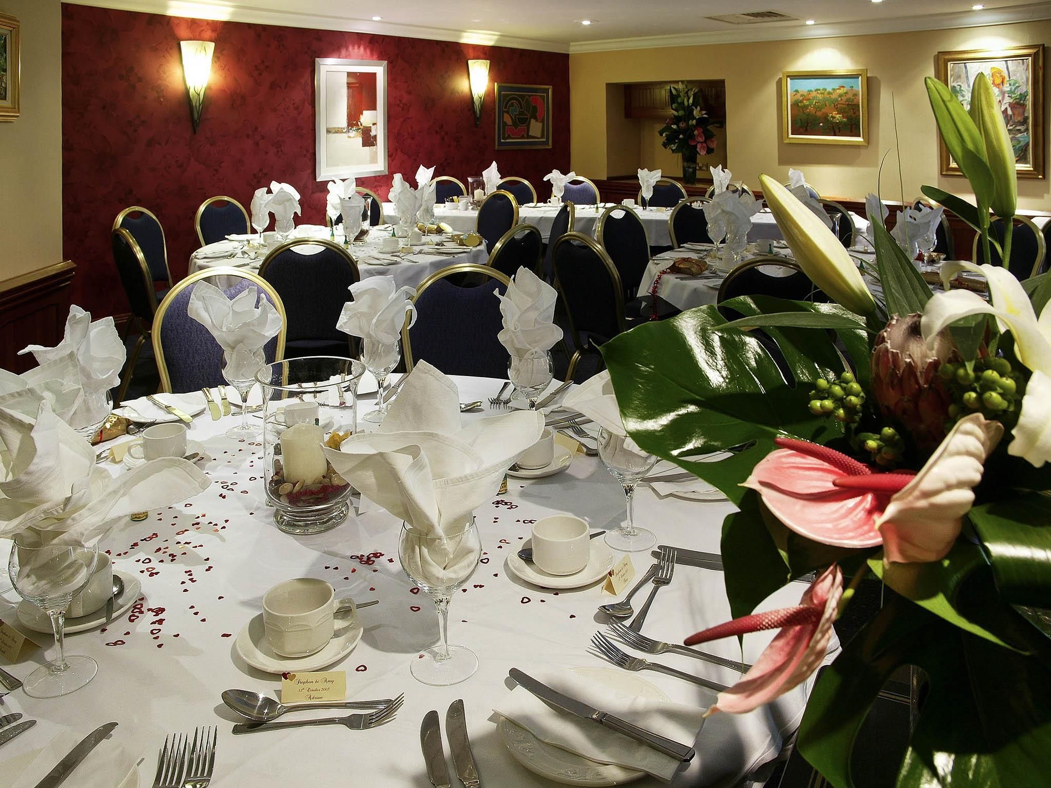 A banquet hall with round tables set for a formal event, complete with white tablecloths, folded napkins, and glassware.