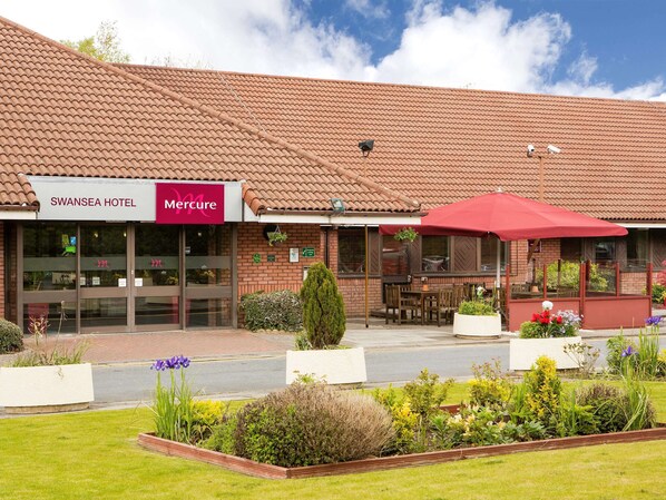 Experience the charm of the Swansea Hotel, surrounded by beautifully maintained gardens and a patio area with outdoor seating.
