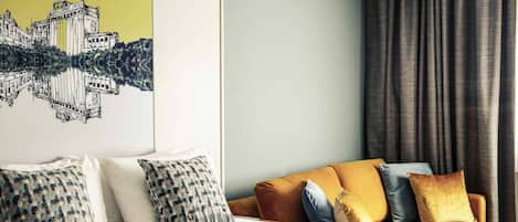 Una habitación de hotel con cama, sofá y un mural con un paisaje urbano en la pared.