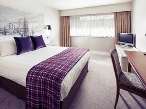 Relax in comfort with a large bed, flat-screen TV, and a spacious desk area.