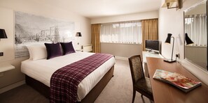 Enjoy a comfortable stay in this well-appointed room featuring a neatly made bed, a spacious desk, and a large window with sheer curtains.
