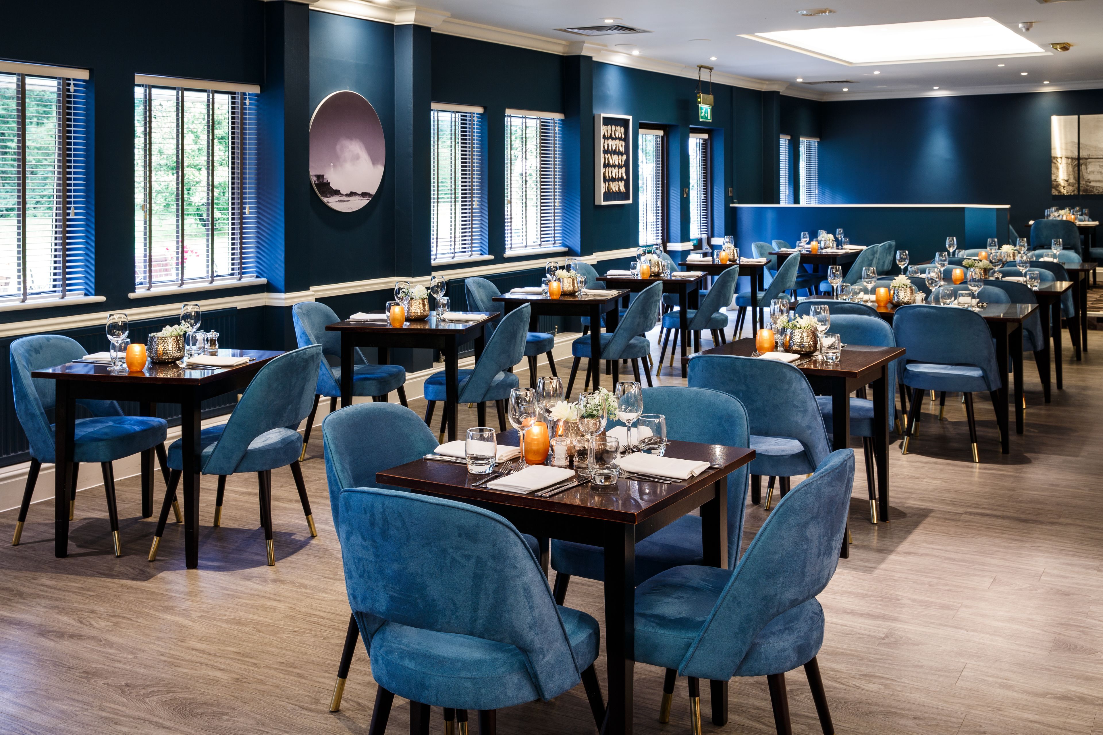 A restaurant with blue chairs and tables, large windows, and a modern interior design.