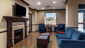 A modern living room with a fireplace, a flat-screen TV mounted above it, a blue sofa, and a dining table with chairs.