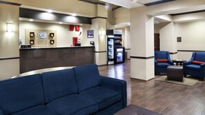 A hotel lobby with a reception desk, a blue sofa, and a seating area with armchairs and a small table.