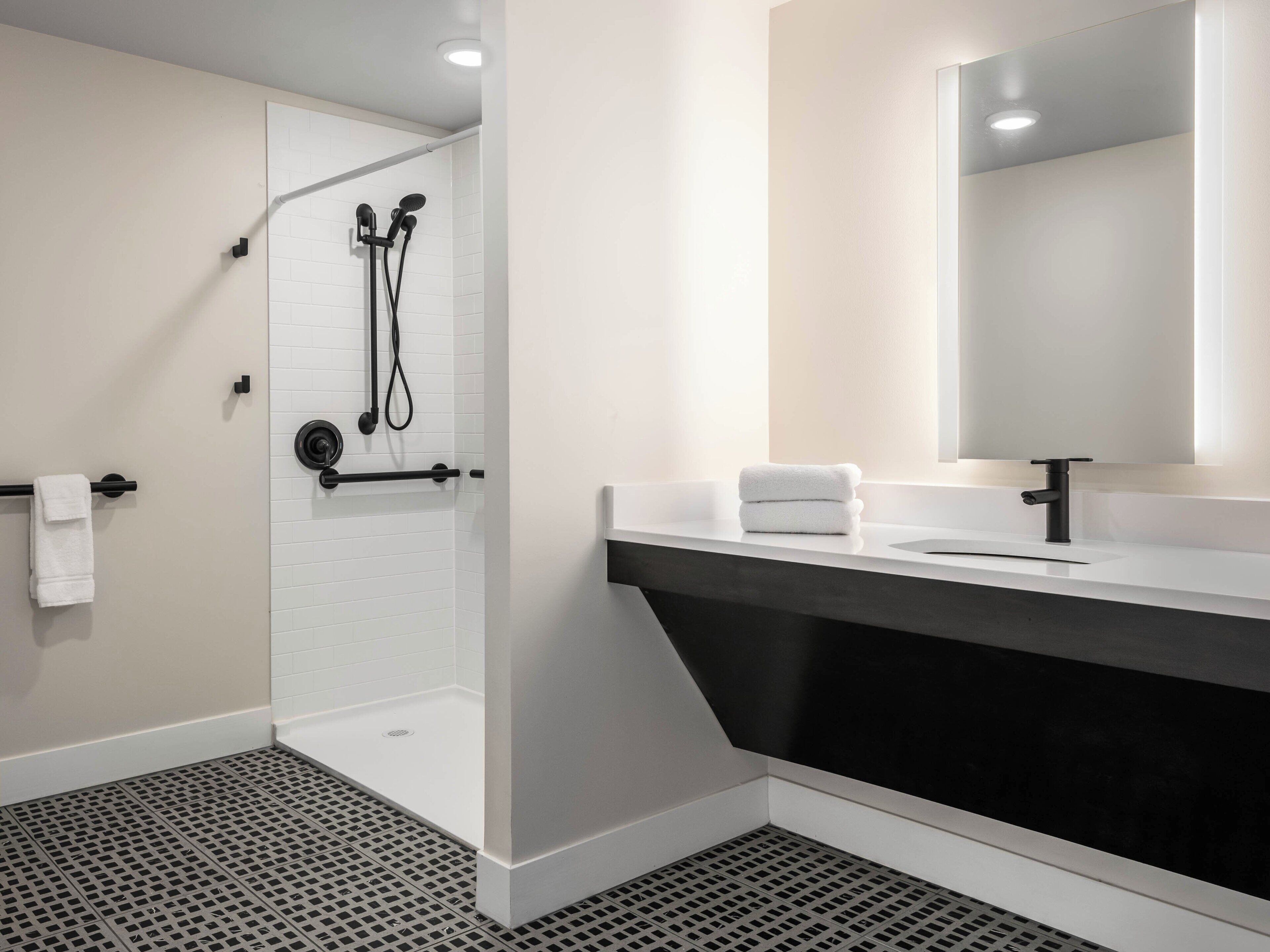 A modern bathroom with a shower, a sink, and a mirror.