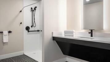 A modern bathroom with a shower, a sink, and a mirror.