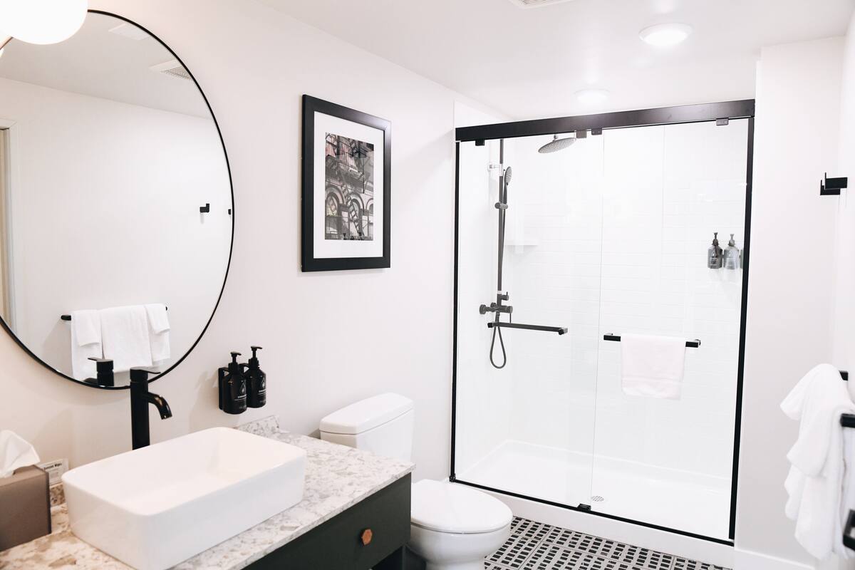 A modern bathroom with a large sink, toilet, and walk-in shower.