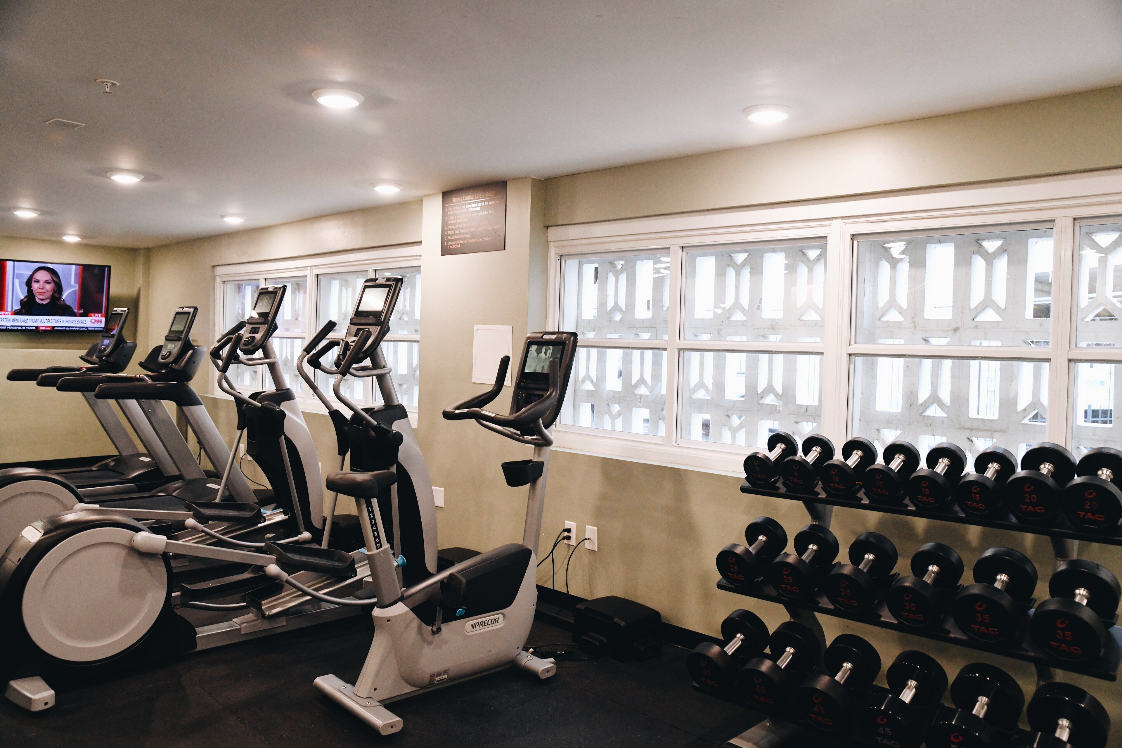 A gym with treadmills, ellipticals, and a rack of dumbbells.