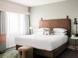 Ein Hotelzimmer mit einem Bett, einer Nachttischlampe und einem kleinen Tisch mit einer Pflanze.