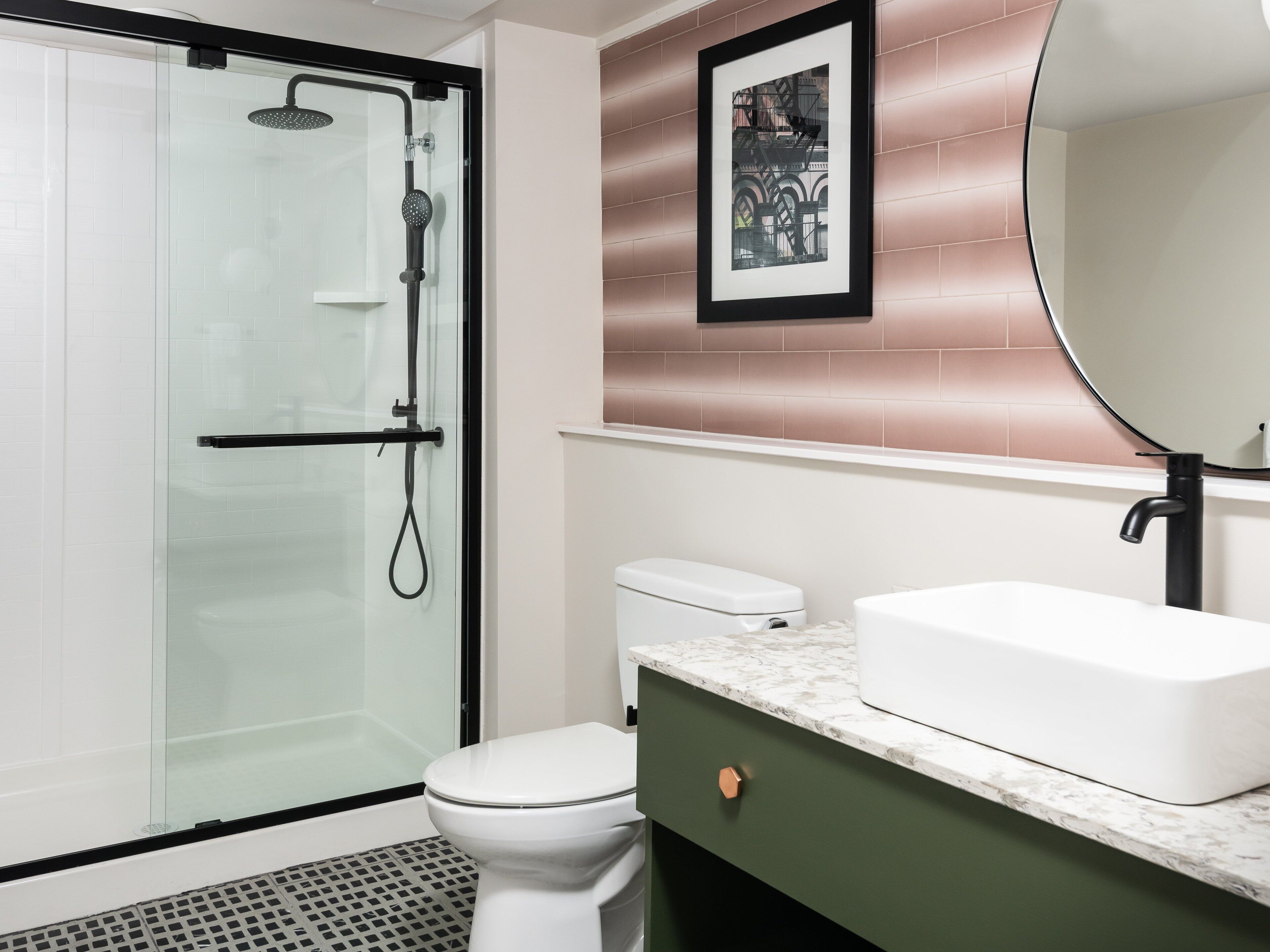 A modern bathroom with a glass-enclosed shower, a white toilet, a marble countertop, and a large mirror.