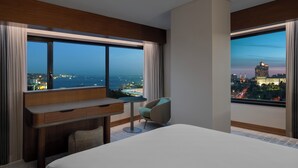 A hotel room with a large bed, a desk, a chair, and a view of the cityscape. - DoubleTree by Hilton Istanbul Macka (Istanbul)