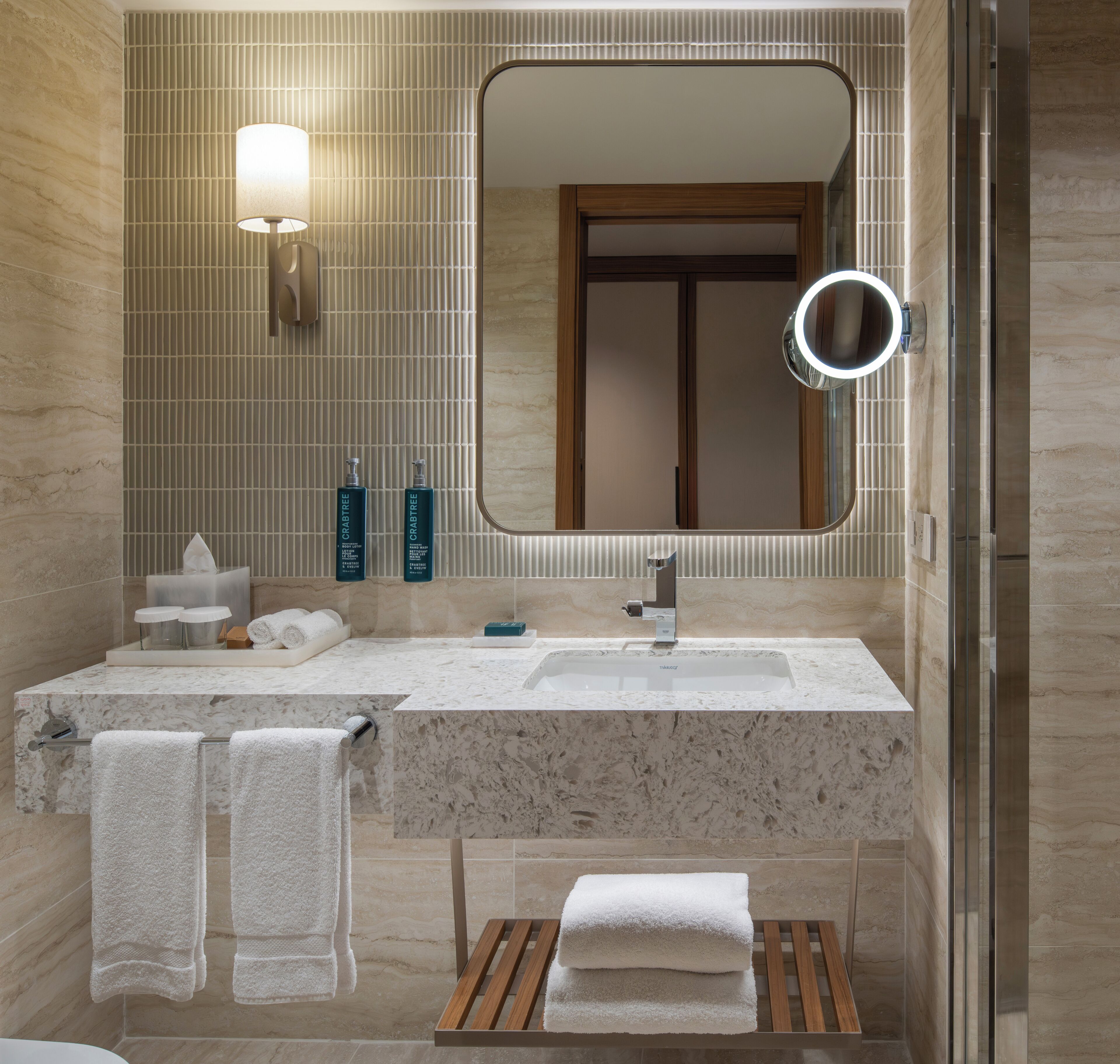 A bathroom with a marble sink, a mirror, and two bottles of Crabtree hand soap.