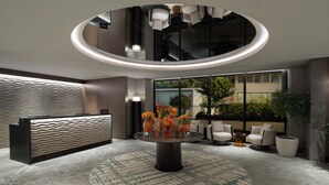 A modern lobby with a reception desk, a round table with vases, and seating areas. - DoubleTree by Hilton Istanbul Macka (Istanbul)