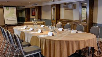 A conference room with a round table, chairs, name cards, water bottles, and a presentation screen.
