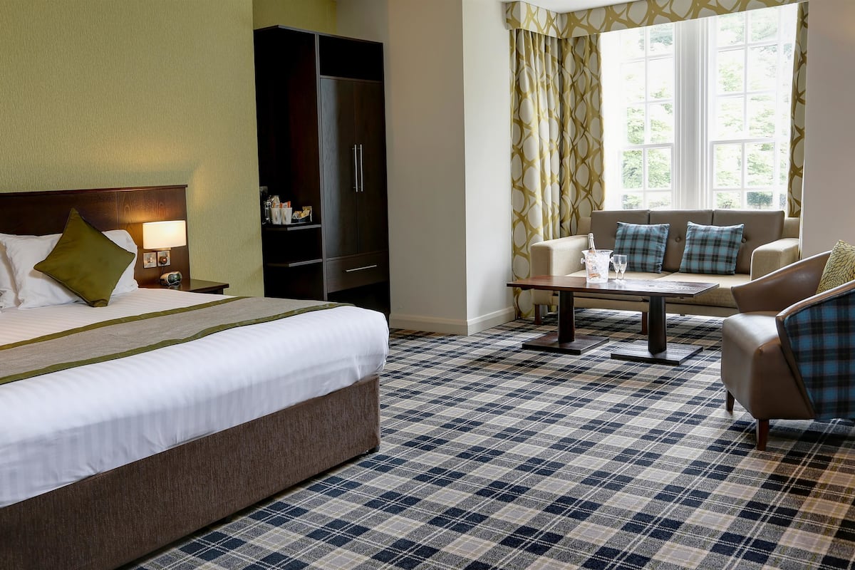 Ein Hotelzimmer mit einem großen Bett, einer Couch, einem Tisch und einem Kleiderschrank.