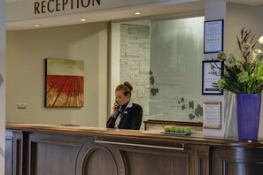 Een receptie met een receptioniste, een inlijsting en een plant.