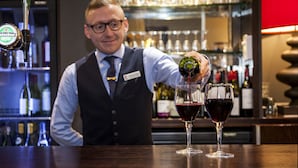 A bartender pouring a drink into a glass.