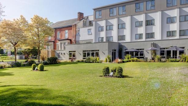 A modern hotel with a spacious courtyard, multiple balconies, and outdoor seating areas.