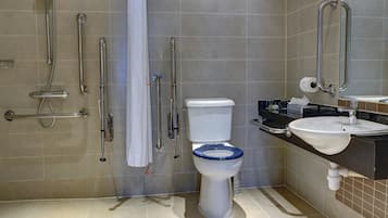 Een badkamer met toilet, wastafel en douche, voorzien van handgrepen.
