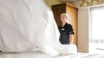 Een hotelkamer met een bed, een houten garderobe en een raam met gordijnen.