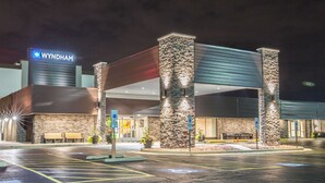 A Wyndham hotel entrance with a stone facade, a covered parking area, and a sign indicating handicap accessibility. - Wyndham Chicago O'Hare (Des Plaines)