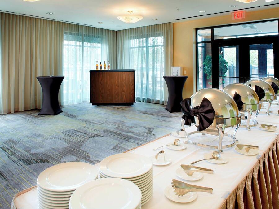 A banquet hall with a long table set for a formal event, featuring stacked plates and elegant tableware.