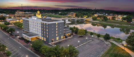 Ein mehrstöckiges Hotel mit Innenhof, Parkplatz und einem Fluss im Hintergrund.