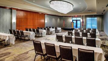 A conference room with multiple tables and chairs, a chandelier, and an American flag.