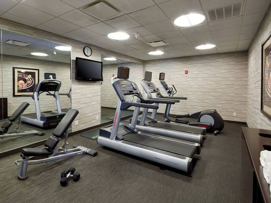 Et fitnessrum med løbebånd, bænk og håndvægte.