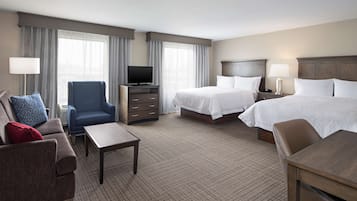 Quarto de hotel com duas camas, televisão, escrivaninha e uma cadeira.